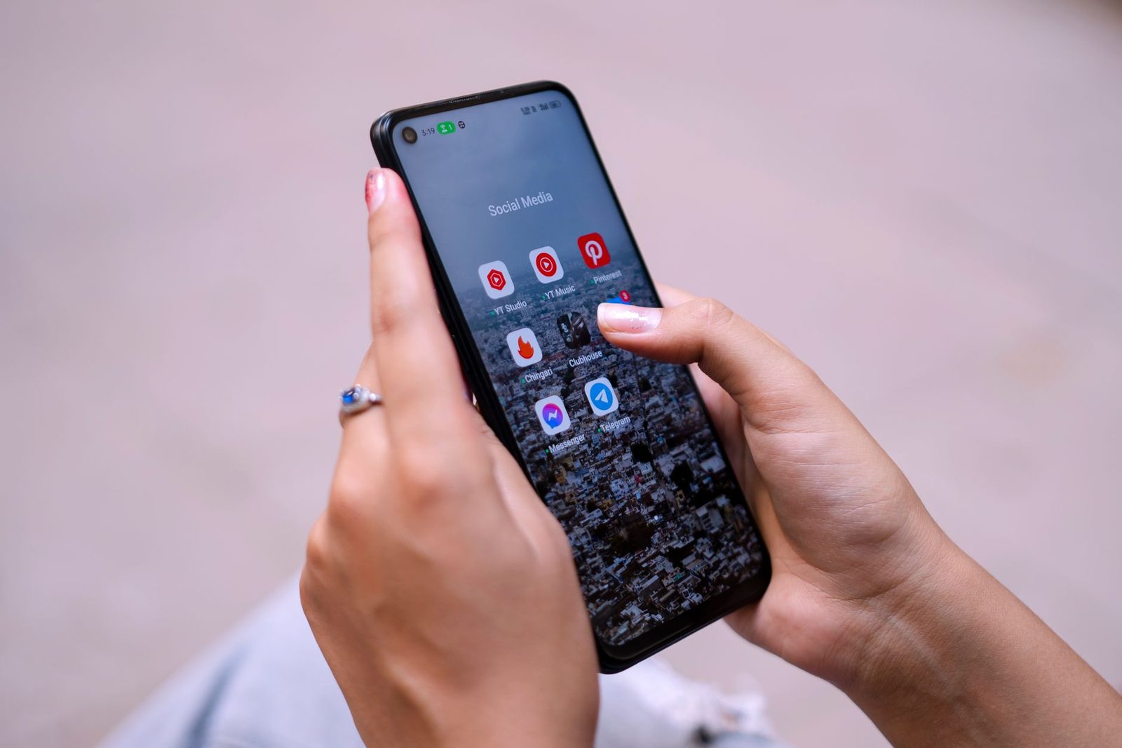 Hand mit einem Smartphone, das einen Ordner mit Social-Media- und Messaging-Apps anzeigt