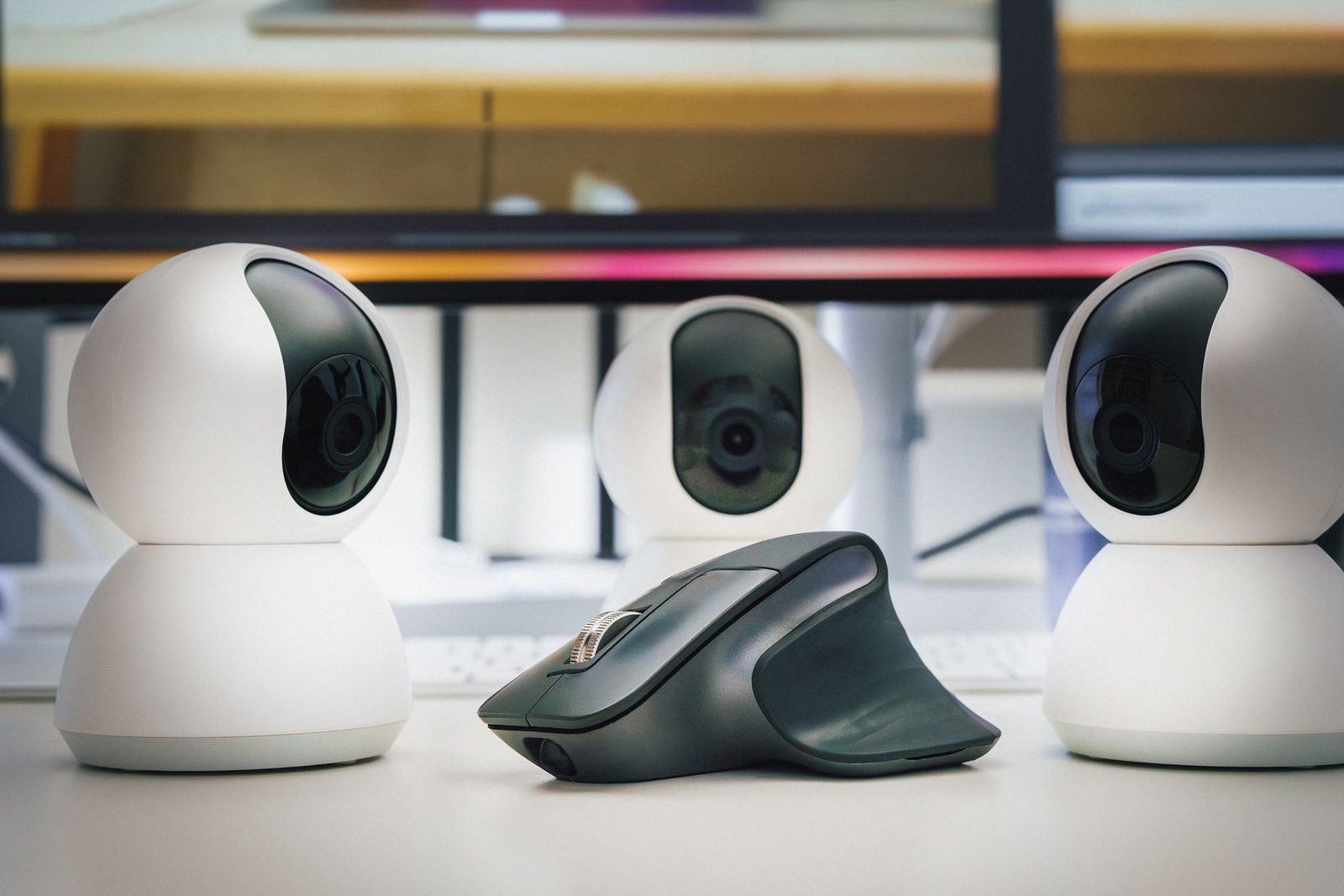 Drei weiße Webcams und eine kabellose Maus auf einem Schreibtisch vor einem Computerbildschirm