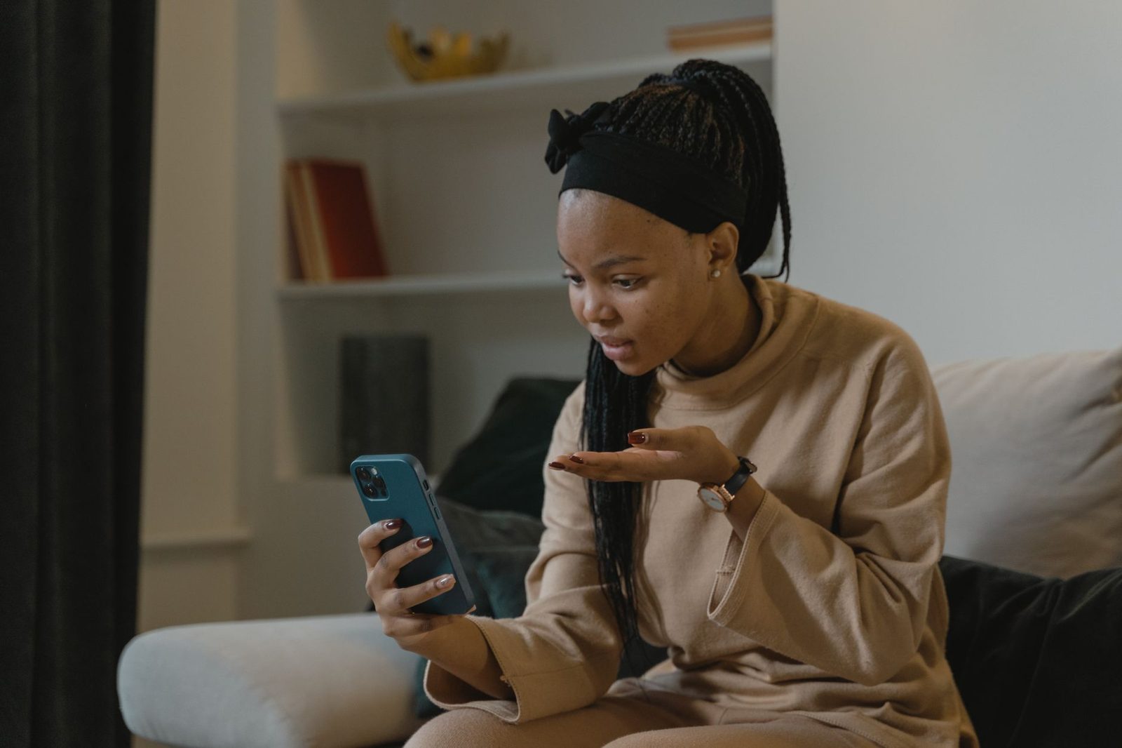 Junge Frau auf einem Sofa mitten in einem Videogespräch auf ihrem Smartphone