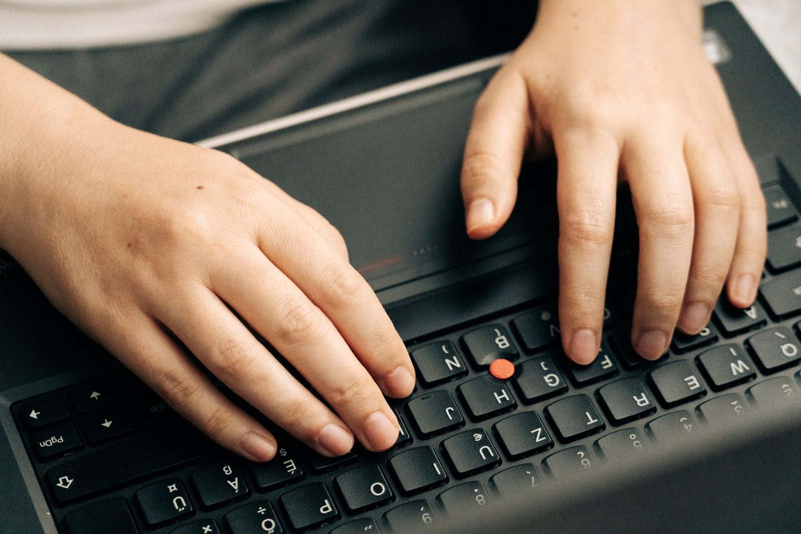 لقطة قريبة ليدين تكتبان على لوحة مفاتيح سوداء لحاسوب محمول